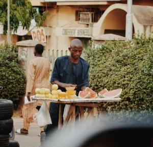 a man standing outside at an open fruit stand