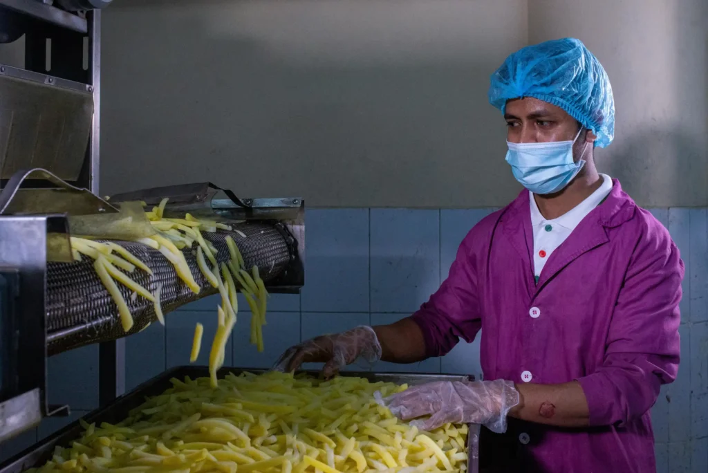 Food processing worker following hygiene practices on a production floor